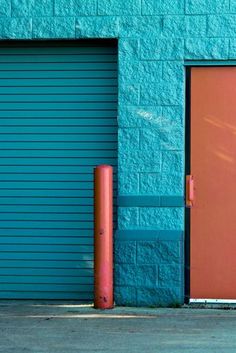 an orange fire hydrant in front of a blue building with a red door on the side