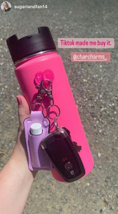 a person holding a pink water bottle with a cell phone attached to it and a keychain