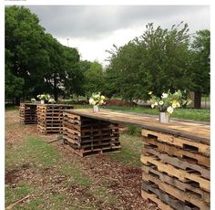 several wooden pallets stacked on top of each other with vases filled with flowers