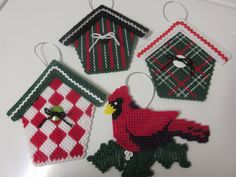 four christmas ornaments made to look like birdhouses and cardinals are hanging from strings