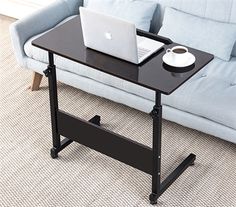 a laptop computer sitting on top of a black table next to a blue couch in a living room