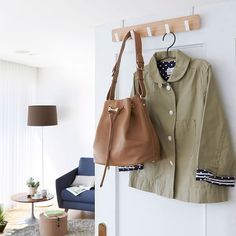 a purse hanging on the wall next to a coat rack and handbag hanger