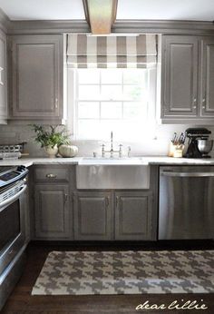 a kitchen with stainless steel appliances and gray cabinets, including a dishwasher on the stove