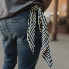 a person wearing blue jeans with a striped tie around their waist