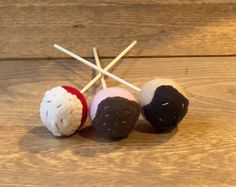 three different colored balls and sticks on a wooden surface