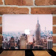 an apple laptop computer sitting on top of a wooden table in front of a brick wall