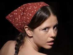 a young woman with freckles on her head looking at the camera while wearing a red bandana