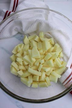 chopped potatoes in a glass bowl on top of a white tablecloth and red striped towel