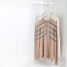 a sweater hanging on a clothes rack in a room with white shelving and shelves