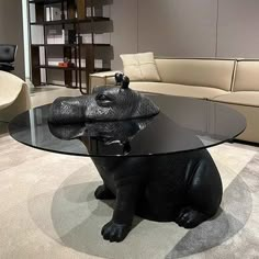 a glass table with an elephant figurine on it in front of a couch