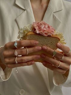 a woman holding a sandwich in her hands with flowers on the bun and rings around it