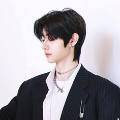 a man with black hair wearing a suit and necklace