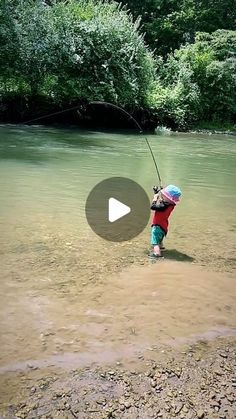 a little boy standing in the water with a fishing rod