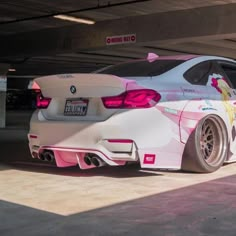 a white car with pink accents parked in a parking garage