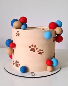 a white cake with red, blue and brown decorations on it's side is decorated with paw prints