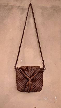 a brown purse hanging on the side of a wall with a tasselled handle