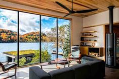 a living room filled with furniture and a large window overlooking a lake surrounded by trees