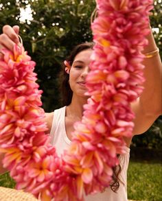 a woman holding up pink flowers in front of her face and arms with both hands