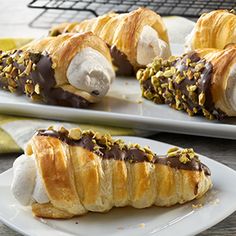 two white plates topped with pastries covered in chocolate and marshmallow toppings