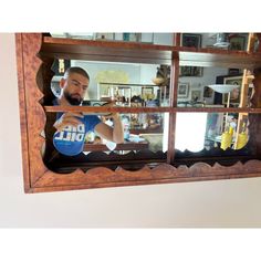 a man standing in front of a mirror with his hands on the window sill