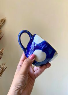 a hand holding a blue and white coffee cup