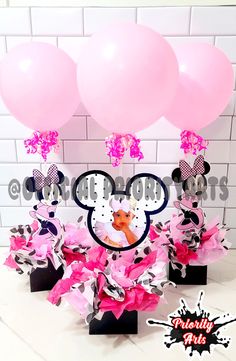 pink and black minnie mouse centerpieces with balloons in front of a brick wall