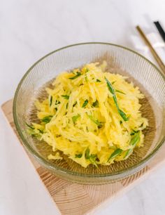 a glass bowl filled with food on top of a wooden cutting board