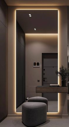 a modern bathroom is lit up with dim lighting and a round ottoman in front of the mirror