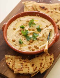 hummus and pita chips on a cutting board