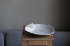 a white plate sitting on top of a wooden table next to a gray couch in a living room