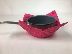 a bowl with a spoon in it sitting on top of a pink cloth covered container