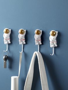 three white teddy bears are hanging on the wall with keys in each one's hooks