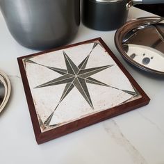 a white and brown star tile on a table next to pot holders with pots in the background