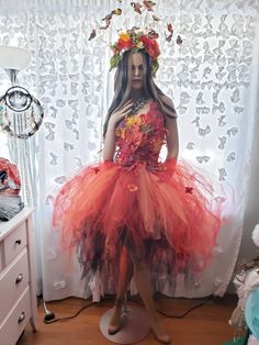 a mannequin dressed in an orange dress with flowers on it's head