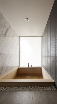 a large bathtub in the middle of a room with rocks on the floor and walls