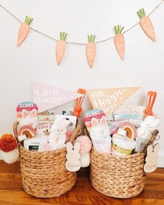 two baskets filled with baby items sitting on top of a wooden floor next to a bunting banner