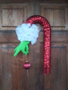 a red and white christmas decoration hanging on the front door with a candy cane attached to it