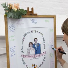 a woman writing on a drawing board next to a wall with a wedding photo drawn on it