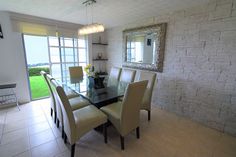 a dining room table with chairs and a mirror on the wall above it, in front of a brick wall