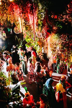 a group of people standing around each other in front of trees and plants at night