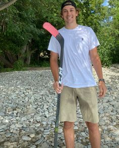 a man standing in front of some rocks holding a ski pole and snowboard poles