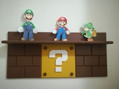 three figurines sitting on top of a shelf with a question mark in front of them