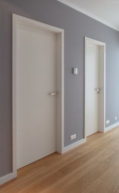 an empty room with white doors and wood floors