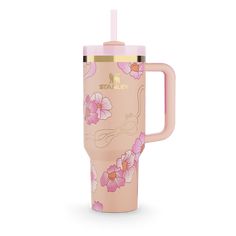 the travel mug is decorated with flowers and has a straw in its cup holder,