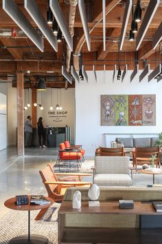 a living room filled with furniture and lots of wood beams hanging from the ceiling above