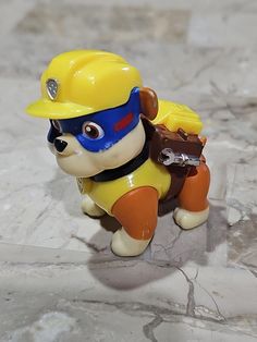 a toy dog wearing a hard hat and carrying a bag