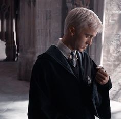 a man with white hair wearing a harry potter robe and holding a wand in his hand