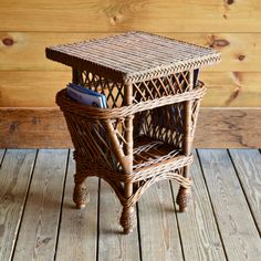 a wicker table with a cell phone on it sitting on a wooden floor next to a wood wall