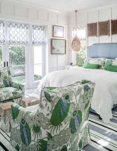 a bedroom with green and white decor in the room, including two chairs and a bed