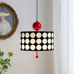 a black and white lamp hanging from a ceiling next to a painting on the wall